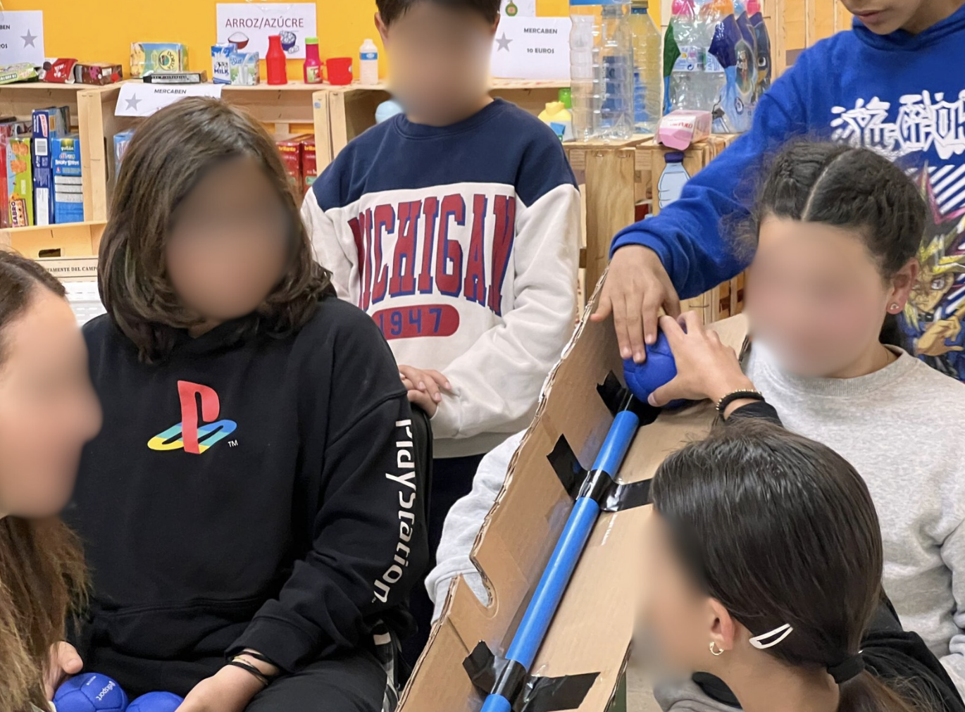 Fotografía na que se poden ver nenos xogando á boccia con material autoconstruído como cartón, picas...