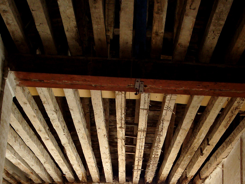 Foto del techo de un edificio antiguo donde se aprecia el forjado de madera de la estructura.