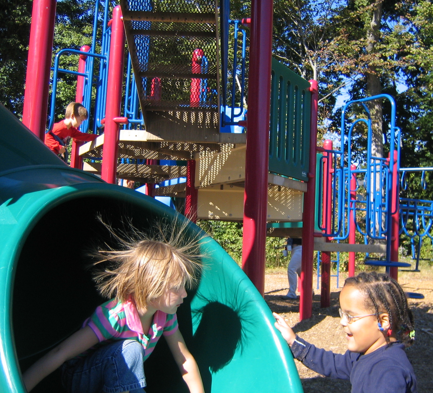 Foto de unos niños jugando en un tobogán con el pelo "electrizado".