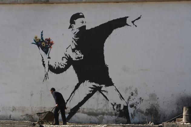Graffiti de Bansky: un hombre que parece ir a arrojar un cóctel molotov en realidad tiene en su lugar un ramo de flores