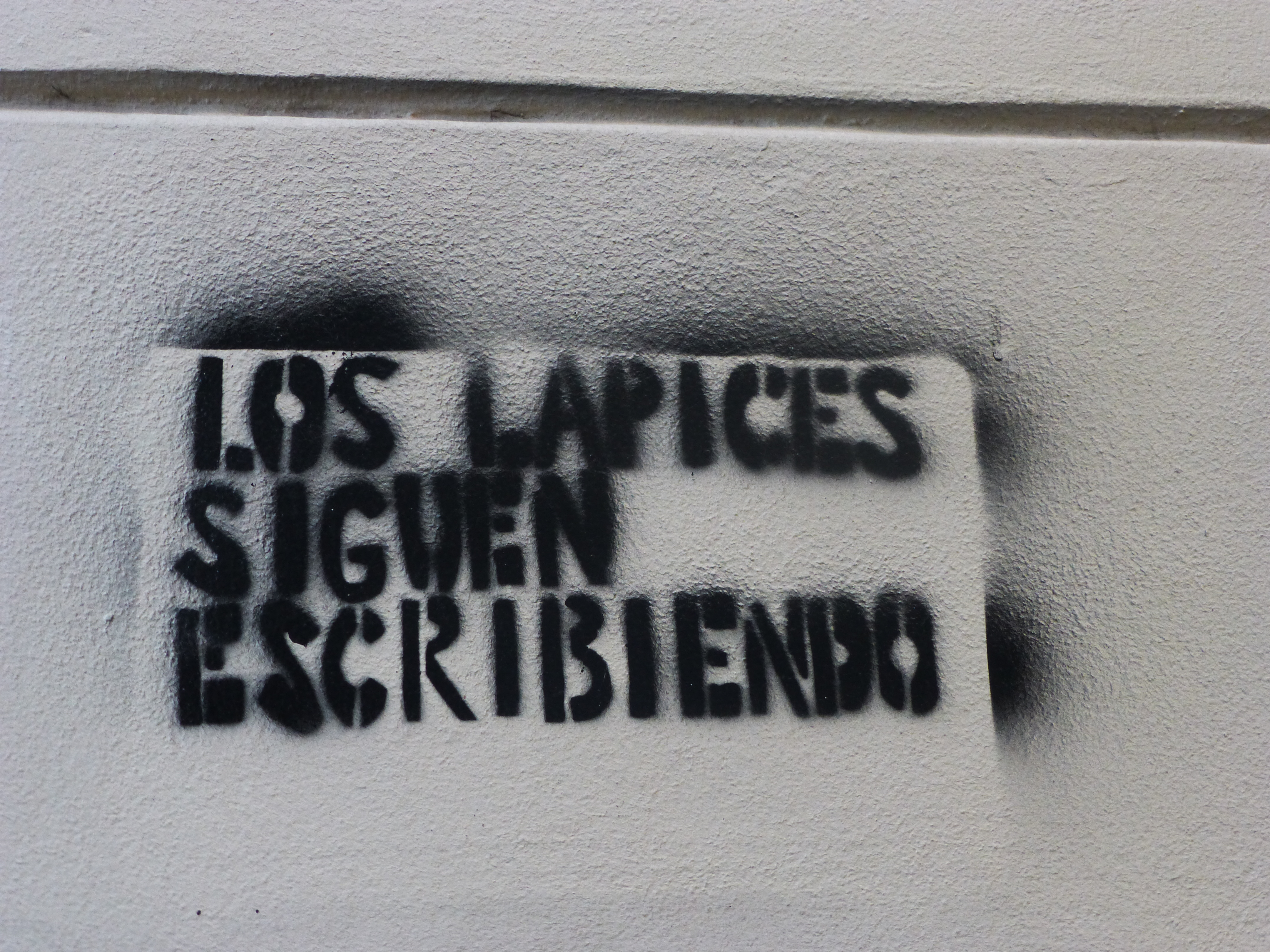 Frase en una pared: "Los lápices siguen escribiendo"