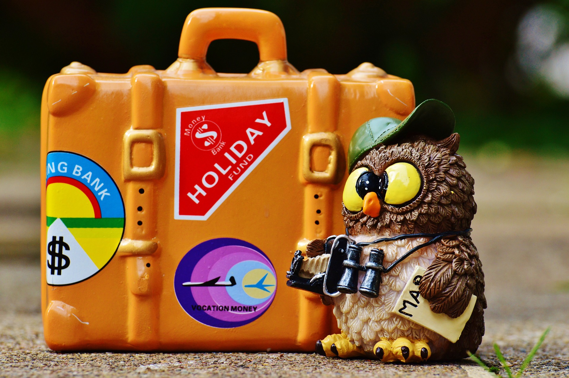 Figura de un búho turista junto a una maleta