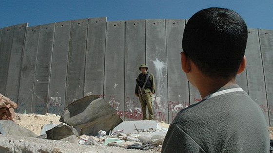 Imagen de un niño palestino ante el muro israelí defendido por un soldado