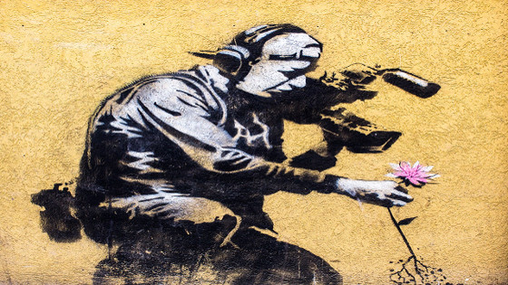 Graffiti de Bansky en el que un cámara se acerca a coger una flor mientras graba la escena