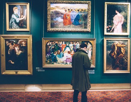 Un homme devant des tableaux dans un musée