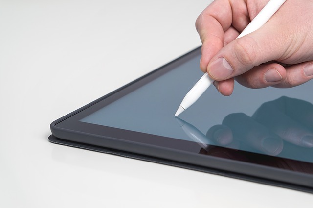 Foto dunha man escribindo nunha tablet cun lapis.