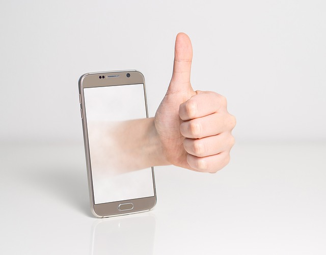 Fotografía dun "Smartphone" do que sae unha man coa posición de "ok".