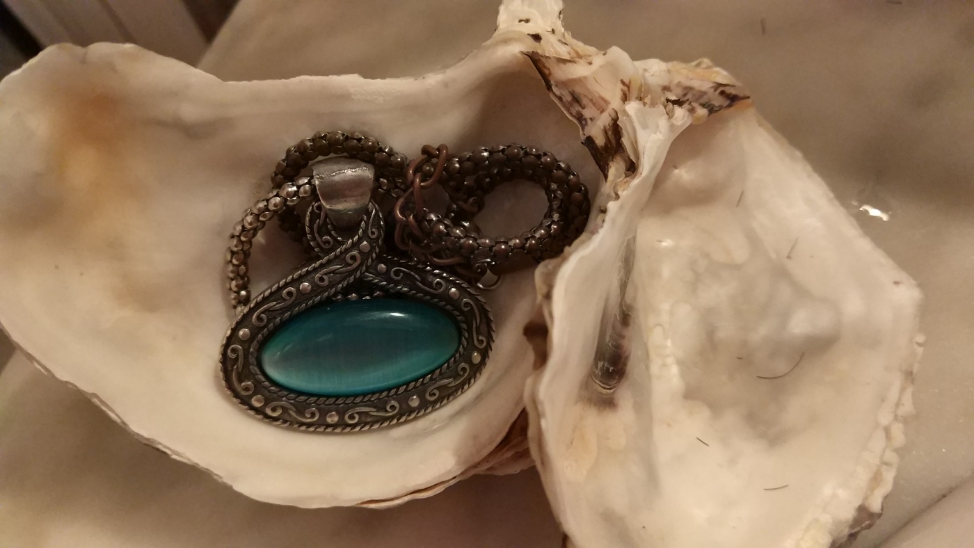 colgante de prata con pedra azul dentro dunha cuncha de ostra