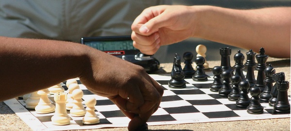 Fotografía de dos personas jugando al ajedrez. Detalle manos y piezas