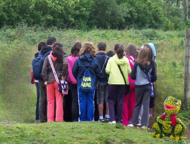 Un grupo de nenas e nenos escoita unha explicación na ruta