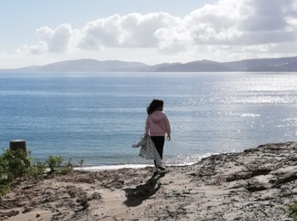 Unha nena mira cara ao mar desde un lugar elevado