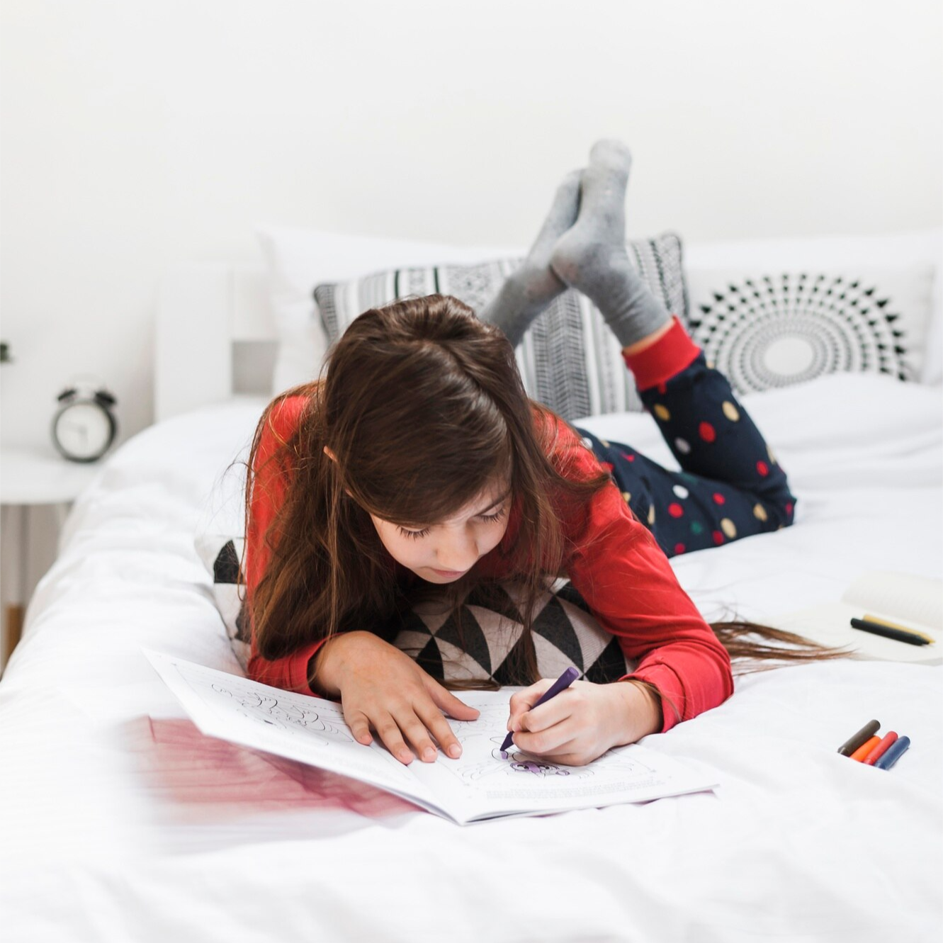 Girl colouring on a bed