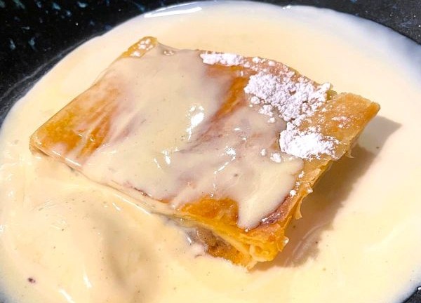 Trozo de tarta de manzana bañada en salsa de nata