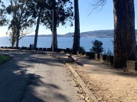 Paseo por las playas donde se ve el mar, hay un camino y árboles alrededor