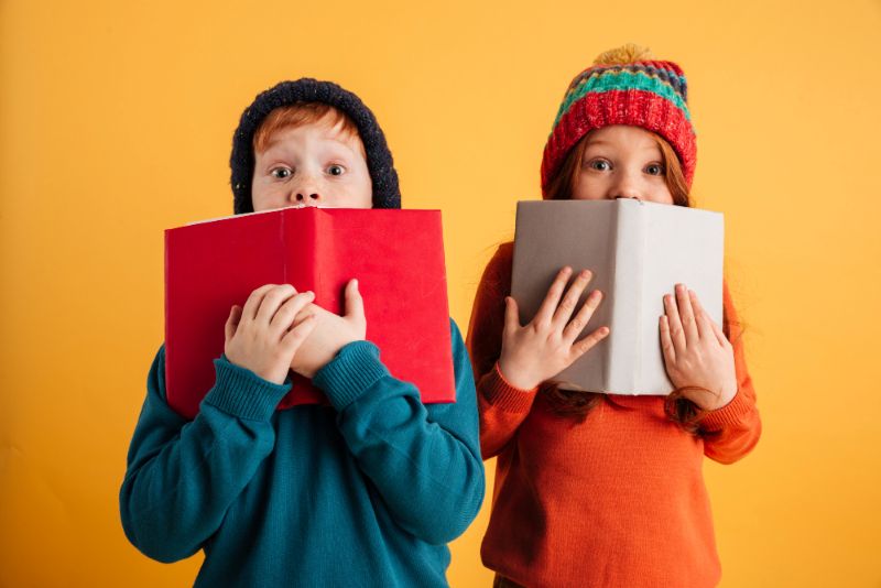 Dos niños tapándose tras dos libros