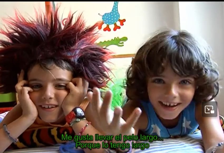 Fotograma de La peluca de Luca Luca con la peluca y su amigo encima de la cama