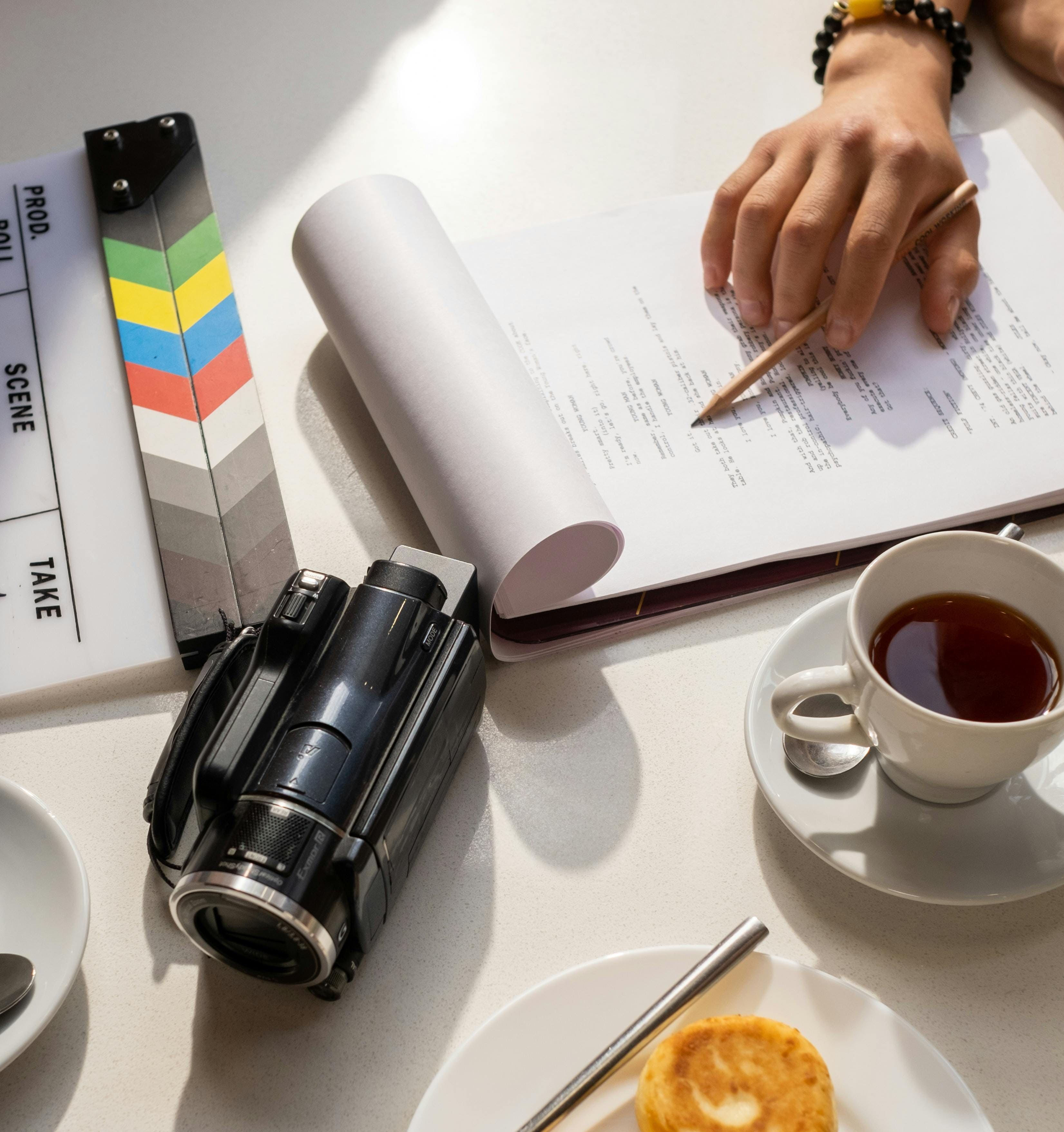 Mesa con camara de video, escaleta de cine y guion en un papel