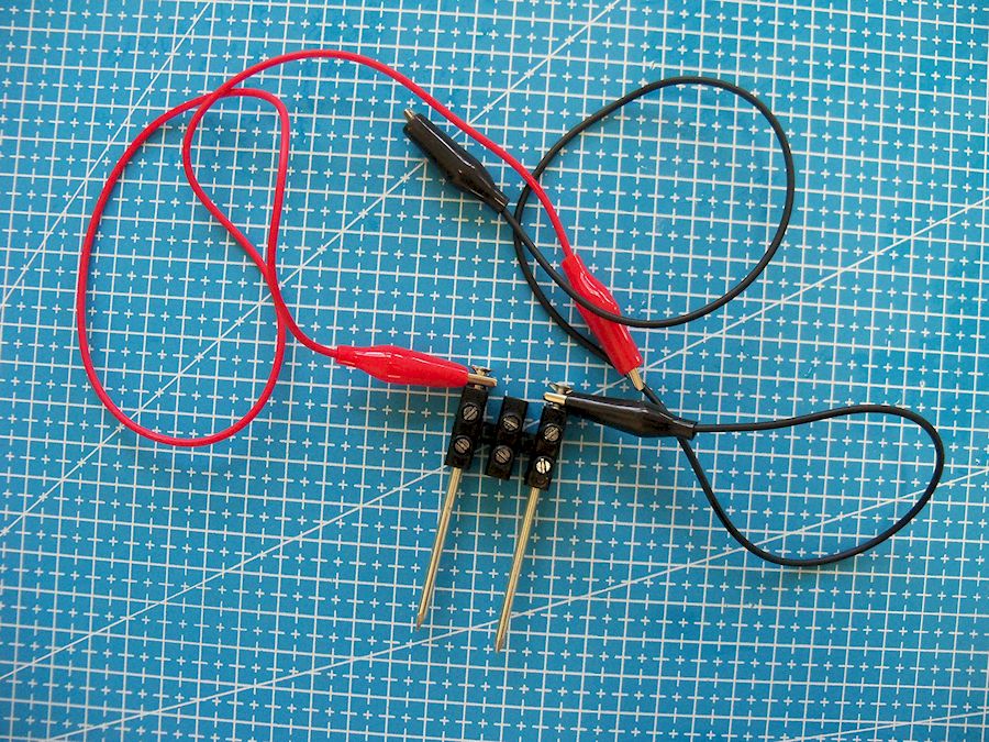 Regreta de electricidade con dous cravos conectados con cables