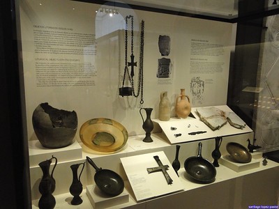 Imaxe que mostra a vitrina dun museo con diferentes obxectos, como vasillas e pratos metálicos