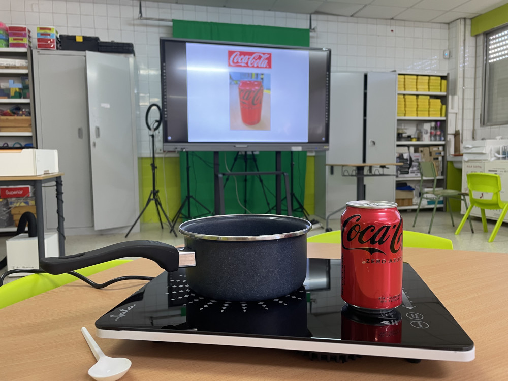 Un refresco, unha cazarola e unha cociña portátil nun laboratorio.