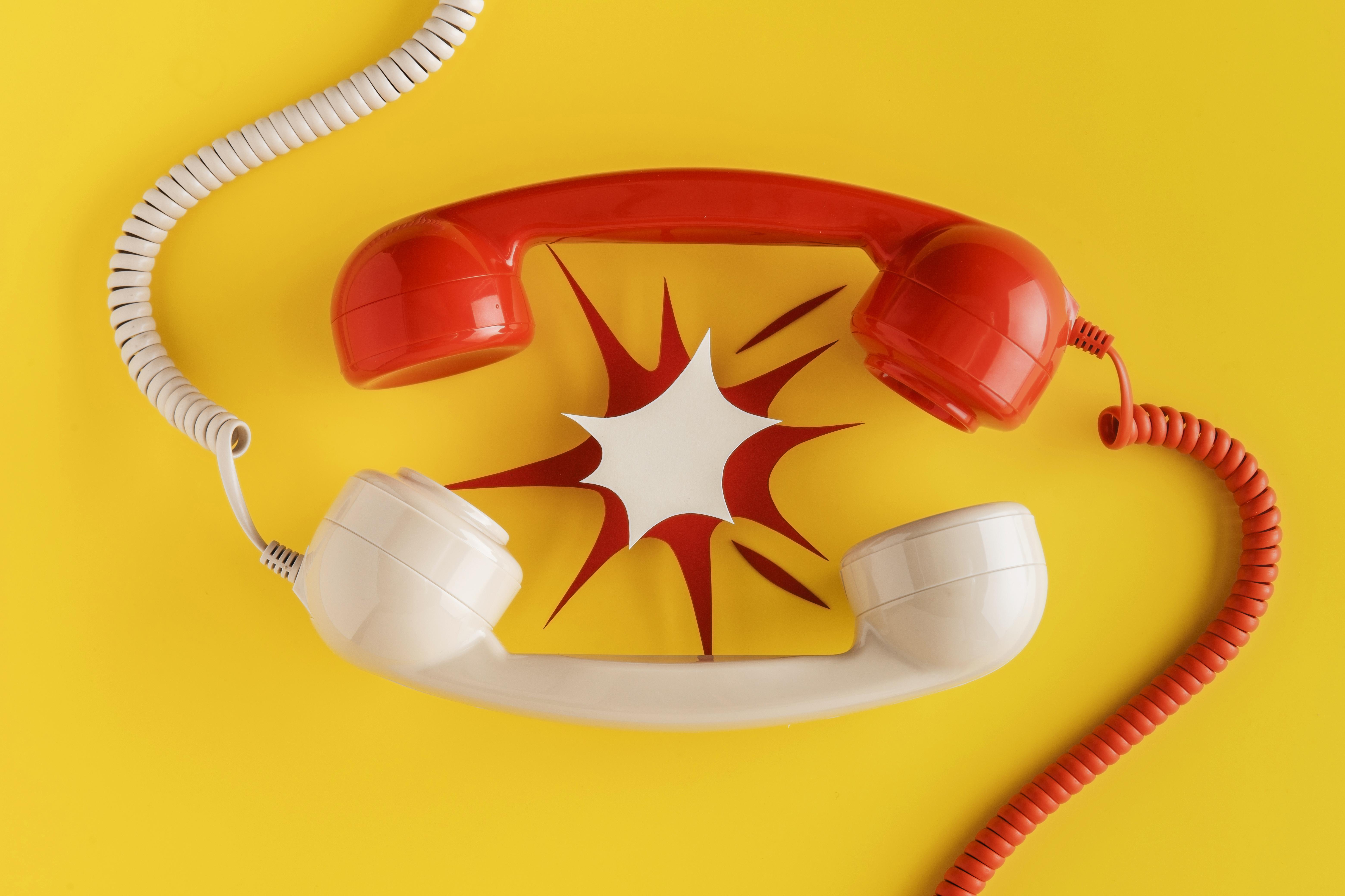 Teléfono estropeado Teléfono rojo y teléfono blanco con explosión de papel en medio