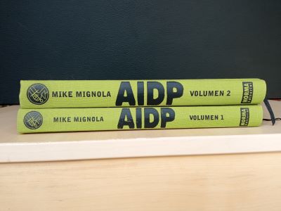Lote de libros 0 (cREAgal) Volúmenes 1 y 2 del cómic AIDP apilados sobre una mesa