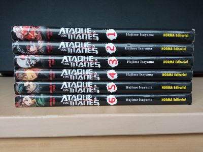 Lote de libros 7 (cREAgal) Volúmenes 1-6 del cómic ATAQUE A LOS TITANES apilados sobre una mesa