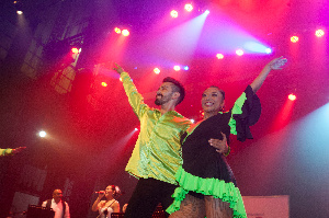 Parella de baile nunha demostración do chachachá nun escenario e saudando ao público.