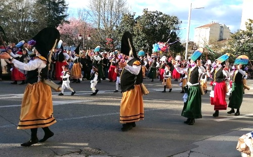 Desfile de carnaval con público y personas desfilando con traje tradicional y gorro de Peliquiero
