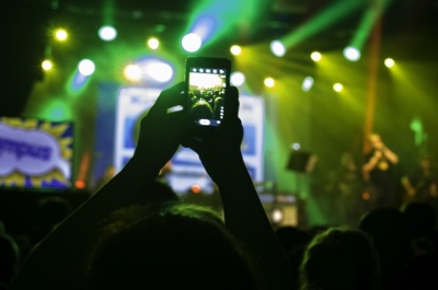 Manos con un móvil sacando una foto al escenario de un concierto