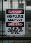 Cartel de peligro alto voltaje en dos idiomas diferentes