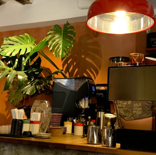 Mostrador de cafetería con cucharas, tenedores, tazas y platos.
