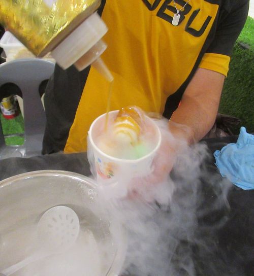 Un vendedor arroja sirope sobre un helado que humea por el nitrógeno líquido