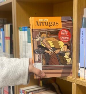 Una persona cogiendo un libro en una biblioteca