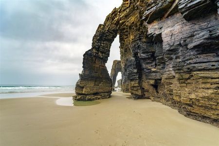 Playa de As Catedrais en Ribadeo erosionada por el impacto de las olas con huecos entre los acantilados.