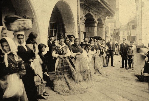 Fotografía antiga de 1900 cun grupo de persoas galegas con traxes tradicionais da época nunha vila