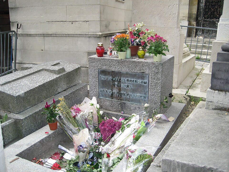 Imaxe na que se ve a tumba de Jim Morrison con flores no cemiterio do Père Lachaise.