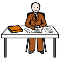 Una persona sentada escribe en su escritorio. Tiene muchos papeles sobre su mesa.