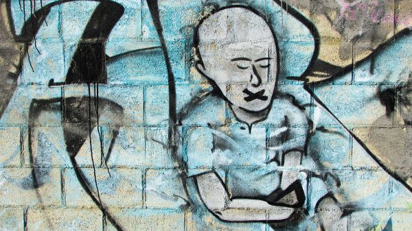 Grafitti que representa censura, una persona con la boca tapada con un cruz negra