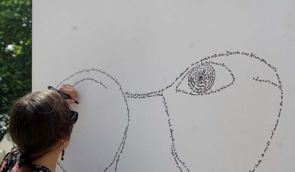 Chico pintando un caligrama en una pared