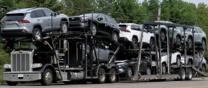 Imaxe que mostra un camión transportando coches novos