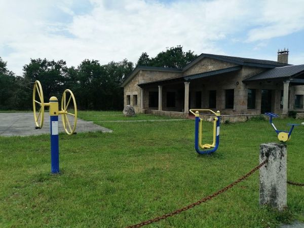 Elementos para hacer gimnasia biosaludable en el exterior en una zona común junto a un local social