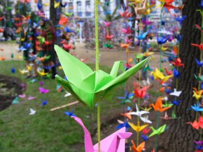 Grúas de papel colgadas por fíos nun parque