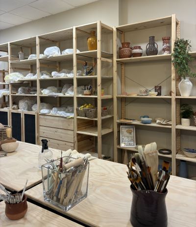 Taller Hedra Cerámica de Santa Cristina. Se ve la mesa de trabajo y al fondo una estantería con muchos diseños de cerámica