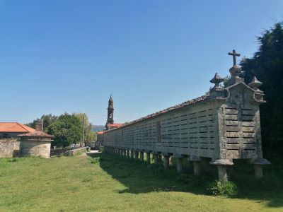 Foto del Hórreo de Carnota con el palomar y la iglesia al fondo