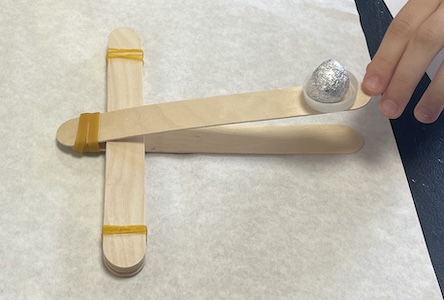 Catapulta de juguete fabricada manualmente con palos madera de helado.