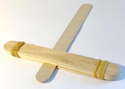 Segundo paso para construir la catapulta. Palos colocados en T con la parte superior atada con gomas elásticas.