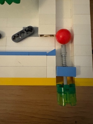 Detalle del muelle lanzador del pinball de piezas de LEGO con una bola roja.