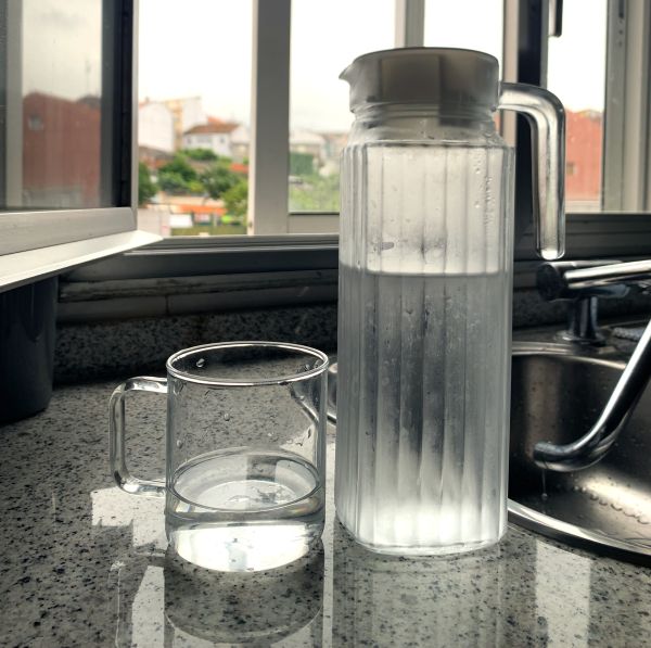 Vaso de agua acompañado de una jarra con agua fría.