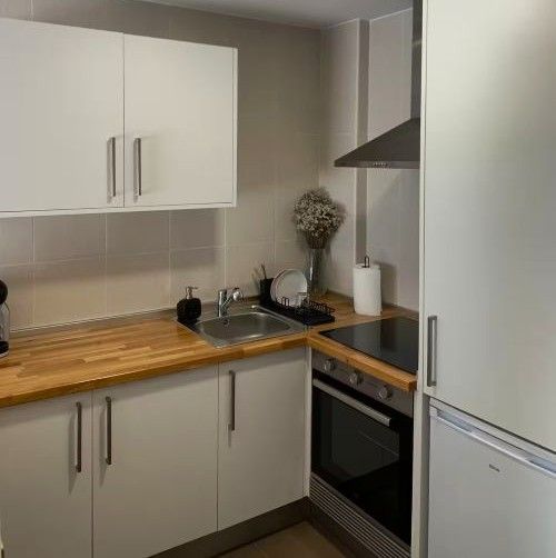 Cocina de apartamento (cREAgal) Cocina con encimera, placa de inducción y campana extractora.